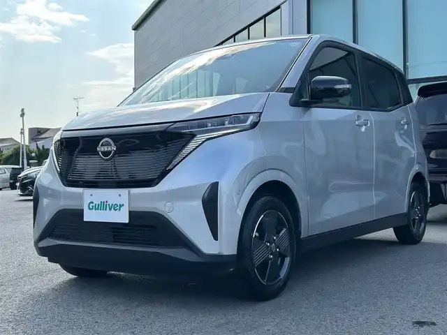 日産 サクラ X 愛媛県 2023(令5)年 0.6万km スターリングシルバーメタリック 禁煙車/登録時走行距離6049km/純正ナビCD/DVD/フルセグTV/Bluetooth/全方位カメラ（フロント/サイド/リヤ）/エマージェンシーブレーキ/踏み間違え防止装置/オートライト/オートハイビーム/LEDヘッドライト/電動パーキングブレーキ/オートブレーキホールド/スマートキー/プッシュスタートボタン/充電ケーブル