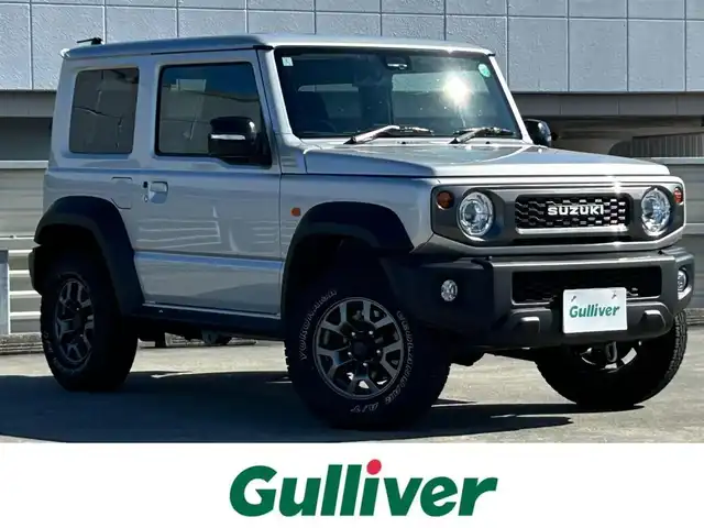 スズキ ジムニー シエラ JC 静岡県 2024(令6)年 0.9万km シルキーシルバーメタリック スズキセーフティサポート/・デュアルセンサーブレーキサポート/・車線逸脱警報機能/・ふらつき警報機能/・先行車発信おしらせ機能/（車両進入禁止/はみ出し禁止/最高速度）/・ハイビームアシスト/社外デジタルインナーミラー/４WD/5速MT/ビルトインETC/クルーズコントロール/シートヒーター/アイドリングストップ/電動格納ミラー（ウィンカーミラー/ミラーヒーター）/純正オプションロッドホルダー/ヘッドラインプウォッシャー/ホワイト照明マルチインフォメーションディスプレイ/革巻きステアリング/プライバシーガラス/ジオランダーG015（人気のホワイトレター）タイヤ