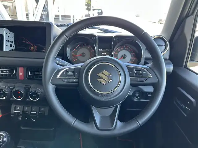 スズキ ジムニー シエラ JC 静岡県 2024(令6)年 0.9万km シルキーシルバーメタリック スズキセーフティサポート/・デュアルセンサーブレーキサポート/・車線逸脱警報機能/・ふらつき警報機能/・先行車発信おしらせ機能/（車両進入禁止/はみ出し禁止/最高速度）/・ハイビームアシスト/社外デジタルインナーミラー/４WD/5速MT/ビルトインETC/クルーズコントロール/シートヒーター/アイドリングストップ/電動格納ミラー（ウィンカーミラー/ミラーヒーター）/純正オプションロッドホルダー/ヘッドラインプウォッシャー/ホワイト照明マルチインフォメーションディスプレイ/革巻きステアリング/プライバシーガラス/ジオランダーG015（人気のホワイトレター）タイヤ