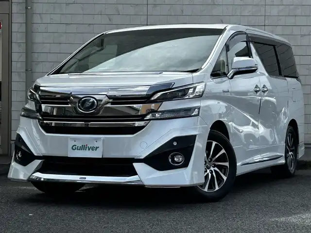 トヨタ ヴェルファイア ハイブリット エグゼクティブ ラウンジ 大分県 2015(平27)年 3.8万km ホワイトパールクリスタルシャイン ワンオーナー/JBLプレミアムサウンド/純正SDナビ/Bluetooth/フルセグ/CD/DVD/モデリスタフルエアロ/Pantneraセキュリティ/全方位カメラ/レーダークルーズコントロール/パワーシート/オットマン/シートメモリー/フリップダウンモニター/100VAC/置くだけ充電（Qi）/社外GPSレーダー/コーナーセンサー/両側パワースライドドア/パワーバックドア/USB・HDMI入力端子/純正アルミホイル17インチ/純正フロアマット/ステアリングスイッチ/ステアリングヒーター/3列シート/オートライト/オートハイビーム/ETC/ドライブレコーダー/チップアップシート/ウッドコンビハンドル/nanoe/スタットレスタイヤ/スペアキー