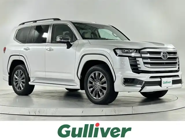 トヨタ ランドクルーザー ZX 佐賀県 2023(令5)年 0.2万km プレシャスホワイトパール 純正12.3インチディスプレイオーディオ（ナビ有）/フルセグTV/CD/DVD/AM/FM/Bluetooth/後席モニター×2/モデリスタエアロ/JBLプレミアムサウンド/ムーンルーフ/クールボックス/指紋認証スタートスイッチ/アラウンドビューモニター/3眼LEDヘッドライト/ETC2.0/ブラインドスポットモニター/レーダークルーズコントロール/レザーシート/パワーシート/シートヒーター/エアシート/ステアリングヒーター/純正20インチアルミホイール/サイドステップ/純正フロアマット/コーナーセンサー/ルーフレール