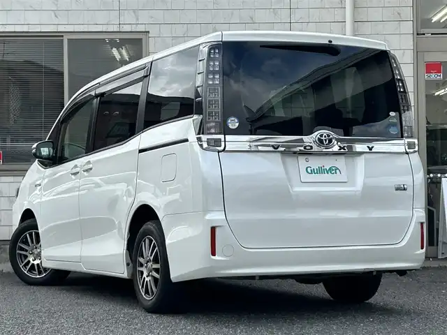 トヨタ ヴォクシー ハイブリッド X 福岡県 2015(平27)年 11.7万km ホワイトパールクリスタルシャイン 後部座席11インチフリップダウンモニター【V11T-R62C】/純正9インチメモリナビ【NSZT-Y64T】/　（AM/FM/CD/DVD/Bluetooth/フルセグTV）/バックカメラ/横滑り防止装置/オートライト/車両接近警報装置/両側パワースライドドア/社外15インチアルミホイール(サーキュラー)/ビルトインETC/コムテック製前後ドライブレコーダー【DC-DR652】/3列シート/社外フロアマット(YMT)/後部座敷サンシェード/電格ウインカーミラー/ドアバイザー/ステアリングスイッチ/電源ソケット×1/ISOFIX/スペアキー×1/保証書/取扱説明書/ナビ取扱説明書