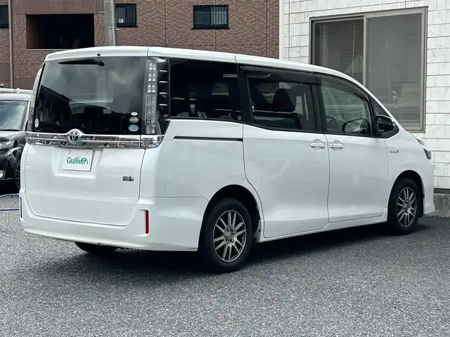 トヨタ ヴォクシー ハイブリッド X 福岡県 2015(平27)年 11.7万km ホワイトパールクリスタルシャイン 後部座席11インチフリップダウンモニター【V11T-R62C】/純正9インチメモリナビ【NSZT-Y64T】/　（AM/FM/CD/DVD/Bluetooth/フルセグTV）/バックカメラ/横滑り防止装置/オートライト/車両接近警報装置/両側パワースライドドア/社外15インチアルミホイール(サーキュラー)/ビルトインETC/コムテック製前後ドライブレコーダー【DC-DR652】/3列シート/社外フロアマット(YMT)/後部座敷サンシェード/電格ウインカーミラー/ドアバイザー/ステアリングスイッチ/電源ソケット×1/ISOFIX/スペアキー×1/保証書/取扱説明書/ナビ取扱説明書