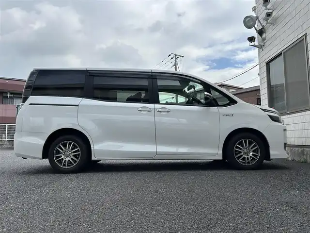 トヨタ ヴォクシー ハイブリッド X 福岡県 2015(平27)年 11.7万km ホワイトパールクリスタルシャイン 後部座席11インチフリップダウンモニター【V11T-R62C】/純正9インチメモリナビ【NSZT-Y64T】/　（AM/FM/CD/DVD/Bluetooth/フルセグTV）/バックカメラ/横滑り防止装置/オートライト/車両接近警報装置/両側パワースライドドア/社外15インチアルミホイール(サーキュラー)/ビルトインETC/コムテック製前後ドライブレコーダー【DC-DR652】/3列シート/社外フロアマット(YMT)/後部座敷サンシェード/電格ウインカーミラー/ドアバイザー/ステアリングスイッチ/電源ソケット×1/ISOFIX/スペアキー×1/保証書/取扱説明書/ナビ取扱説明書
