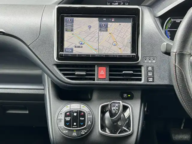 トヨタ ヴォクシー ハイブリッド X 福岡県 2015(平27)年 11.7万km ホワイトパールクリスタルシャイン 後部座席11インチフリップダウンモニター【V11T-R62C】/純正9インチメモリナビ【NSZT-Y64T】/　（AM/FM/CD/DVD/Bluetooth/フルセグTV）/バックカメラ/横滑り防止装置/オートライト/車両接近警報装置/両側パワースライドドア/社外15インチアルミホイール(サーキュラー)/ビルトインETC/コムテック製前後ドライブレコーダー【DC-DR652】/3列シート/社外フロアマット(YMT)/後部座敷サンシェード/電格ウインカーミラー/ドアバイザー/ステアリングスイッチ/電源ソケット×1/ISOFIX/スペアキー×1/保証書/取扱説明書/ナビ取扱説明書