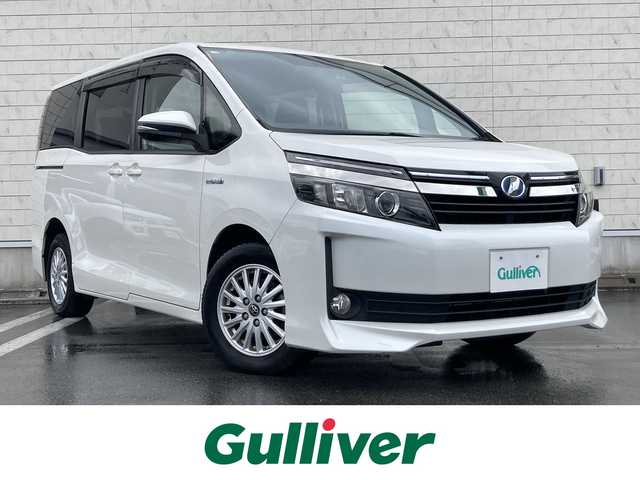 トヨタ ヴォクシー ハイブリッド V 静岡県 2014(平26)年 7.5万km ホワイトパールクリスタルシャイン 社外メモリーナビ(AVIC-RW710)/　AM FM CD DVD Bluetooth SD/ビルトインETC/LEDオートヘッドランプ/シートヒーター(前席)/両側パワースライドドア/クルーズコントロール/革巻きステアリング/ステアリングスイッチ/スマートキー＆プッシュスタート/純正15インチアルミホイール/リアロールサンシェード/フルセグTV/バックモニター/前後方ドライブレコーダー