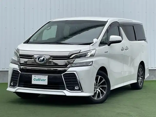 トヨタ ヴェルファイア ハイブリット ZR 香川県 2015(平27)年 8.9万km プレシャスホワイトパール 登録時走行距離：88289km/4WD/純正9インチナビ/→AM/FM/フルセグTV/Bluetooth/→CD/DVD再生/→HDMI入力/JBLプレミアムサウンドシステム/バックカメラ/クルーズコントロール/シートメモリー付きパワーシート/ハーフレザーシート/オットマン/キャプテンシート/両側パワースライドドア/パワーバックドア/LEDオートライト/フォグランプ/オートハイビーム/トヨタセーフティセンス/→プリクラッシュセーフティ/→レーンディパーチャーアラート/→クリアランスソナー/プッシュスタート/スマートキー