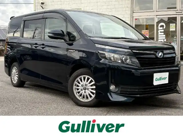 トヨタ ヴォクシー ハイブリッド V 愛知県 2014(平26)年 16.5万km ブラッキッシュアゲハガラスフレーク ワンオーナー/バックカメラ/社外SDナビ/Bluetooth/SD/DVD/CD/社外後席モニター/フルセグTV/3列シート/両側パワースライドドア/クルーズコントロール/ビルトインETC/シートヒーター/置くだけ充電/純正フロアマット/純正アルミホイール/LEDヘッドライト/スペアキー/保証書/取扱説明書