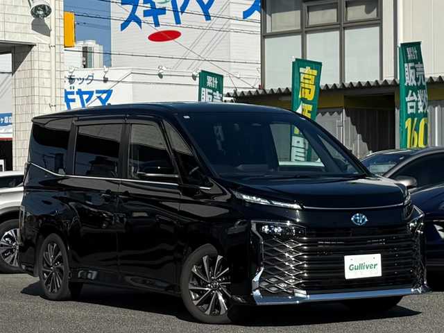 トヨタ ヴォクシー ハイブリッド S－Z 愛知県 2024(令6)年 1.6万km アティチュードブラックマイカ /ワンオーナー車//D記録簿R6-R7//10.5インチディスプレイオーディオ//AM/FM/TV（フルセグ）＋CD・DVDデッキ//BT/USB/Miracast//快適利便パッケージ//ハンズフリーデュアルパワースライドドア//パワーバックドア//1列目2列目シートヒーター//2列目オットマン//2列目角度調整付きアームレスト//ドライビングサポートパッケージ//カラーヘッドアップディスプレイ//デジタルインナーミラー//純正13.2インチ有機EL後席モニター//ETC2.0//レーダークルーズコントロール//ブラインドスポットモニター//レーンディパーチャーアラート//プリクラッシュセーフティー//プロアクティブドライビングシステム//クリアランスソナー//リヤクロストラフィックアラート//リヤカメラディテクション//パーキングサポートブレーキ//安心降車アシスト//ロードサインアシスト//レーンチェンジアシスト//フロントクロストラフィックアラート//アドバンストパーク//パノラミックビューモニター//バックカメラ//オートLEDヘッドライト//オートハイビーム//オートブレーキホールド//電動パーキングブレーキ//ステアリングスイッチ//ステアリングヒーター//AC100V//保証書//取説