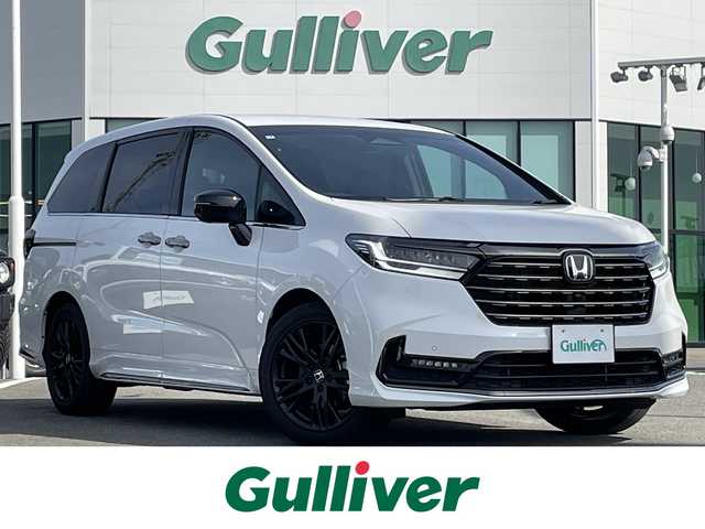 ホンダ オデッセイ ハイブリッド e:HEVアブソルート EXブラックED 熊本県 2025(令7)年 0.7万km プラチナホワイトパール 黒革シート/両側パワースライドドア/パワーテールゲート/電子パーキングブレーキ/・BRAKE HOLD機能/置くだけ充電/後席エアコン/DN席＋2列目パワーシート/シートヒーター/2列目電動オットマン/キャプテンシート/ISOFIX対応/パドルシフト/革巻きステアリング/ステアリングリモコン/純正18インチアルミホイール/純正LEDヘッドライト/・オートマチックハイビーム/純正LEDフォグランプ/新車保証書/取扱説明書/スペアキー１本/ホンダセンシング/・アダプティブクルーズコントロール/・路外逸脱抑制機能/・ブラインドスポットインフォメーション/・踏み間違い衝突軽減システム/・衝突被害軽減ブレーキ/・パーキングセンサーシステム/・標識認識機能