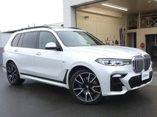 ＢＭＷ Ｘ７ xDrive35d Mスポーツ 静岡県 2020(令2)年 1.9万km ミネラルホワイト ワンオーナー/禁煙車/OP22インチホイール/　Mスポブルーブレーキキャリパー/ウェルネスパッケージ/・コンビエントエアパッケージ/・保冷/保温機能付カップホルダー/・ヒートコンフォートパッケージ/　ステアリングヒーター/アームレストヒーター/リアエンターテインメントシステム/　プロフェッショナル/・左右独立10.2インチディスプレイ/　Blu-ray/HDMIインターフェイス/パーキングアシストプラス/・パークディスタンスコントロール/パーキングアシスト/・トップビュー/3Dビュー/サイドビューカメラ／リアビューカメラ/・リバースアシスト/後退時ステアリングアシスト/ドライビングアシストプロフェッショナル/・アクティブクルーズコントロール/・ステアリング/レーンコントロールアシスト/・レーンディパーチャー/　レーンチェンジウォーニング/・前車接近警告機能/衝突回避/　被害軽減ブレーキ/後車衝突警告機能/スカイラウンジパノラマルーフ/harman/kardonスピーカー/メーカー純正ナビ/　CD/DVD/BT/フルセグTV/ミラー/一体型ETC/純正前後ドライブレコーダー/前席パワーシート/ベンチレーション/マッサージ機能