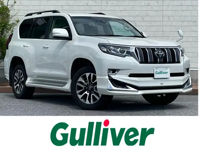 トヨタ ランドクルーザー プラド TX Lパッケージ 滋賀県 2023(令5)年 2.2万km ホワイトパールクリスタルシャイン 4WD/サンルーフ/モデリスタエアロ/オールシーズンタイヤ/ルーフレール/社外9インチナビ【AVIC-CQ912】/（AM/FM/フルセグ/CD/DVD/Bluetooth/HDMI/USB/AUX）/バックカメラ/ビルトインETC/トヨタセーフティセンス/・踏み間違い防止アシスト	/・ブレーキアシスト/・衝突軽減装置/・ヒルスタート（坂道発進）アシスト/・前方衝突防止支援システム/・ABS（アンチロックブレーキシステム）	/・TCS（トラクションコントロールシステム）/・VDC（ビークルダイナミクスコントロール）/・ASCD（オートスピードコントロール装置）/・標識検知機能/・コーナーセンサー/運転席・助手席シートヒーター/運転席・助手席シートベンチレーション/ベージュ革シート/パワーシート/メモリーシート/電動格納ミラー/ステアリングスイッチ/オートライト/オートハイビーム/LEDヘッドライト/フロントフォグ/フルオートエアコン/プッシュスタート/スマートキー/純正フロアマット積込/純正シフトノブ積込