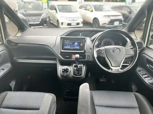 トヨタ ヴォクシー ZS 煌 大分県 2015(平27)年 9.1万km ホワイトパールクリスタルシャイン ・社外メモリーナビ（MDV-Z701W）/　CD/DVD/BT/フルセグ/・ETC/・両側パワースライドドア/・社外フリップダウンモニター/・革巻きステアリング/・スマートキー/・エンジンプッシュスタート/・ウインカーミラー/・ステアリングスイッチ/・フロアマット/・ドアバイザー/・プライバシーガラス/・アイドリングストップ/・横滑り防止システム/・後部座席サンシェード/・純正16インチアルミホイール/・LEDヘッドライト/・純正フォグランプ/・保証書/・取扱説明書