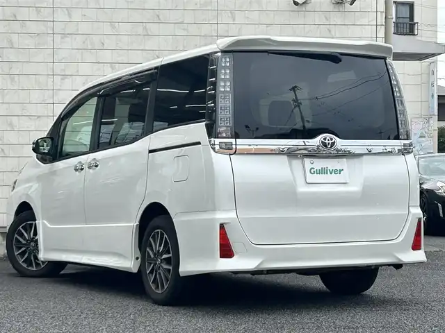 トヨタ ヴォクシー ZS 煌 大分県 2015(平27)年 9.1万km ホワイトパールクリスタルシャイン ・社外メモリーナビ（MDV-Z701W）/　CD/DVD/BT/フルセグ/・ETC/・両側パワースライドドア/・社外フリップダウンモニター/・革巻きステアリング/・スマートキー/・エンジンプッシュスタート/・ウインカーミラー/・ステアリングスイッチ/・フロアマット/・ドアバイザー/・プライバシーガラス/・アイドリングストップ/・横滑り防止システム/・後部座席サンシェード/・純正16インチアルミホイール/・LEDヘッドライト/・純正フォグランプ/・保証書/・取扱説明書