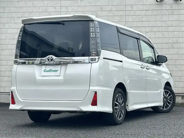 トヨタ ヴォクシー ZS 煌 大分県 2015(平27)年 9.1万km ホワイトパールクリスタルシャイン ・社外メモリーナビ（MDV-Z701W）/　CD/DVD/BT/フルセグ/・ETC/・両側パワースライドドア/・社外フリップダウンモニター/・革巻きステアリング/・スマートキー/・エンジンプッシュスタート/・ウインカーミラー/・ステアリングスイッチ/・フロアマット/・ドアバイザー/・プライバシーガラス/・アイドリングストップ/・横滑り防止システム/・後部座席サンシェード/・純正16インチアルミホイール/・LEDヘッドライト/・純正フォグランプ/・保証書/・取扱説明書