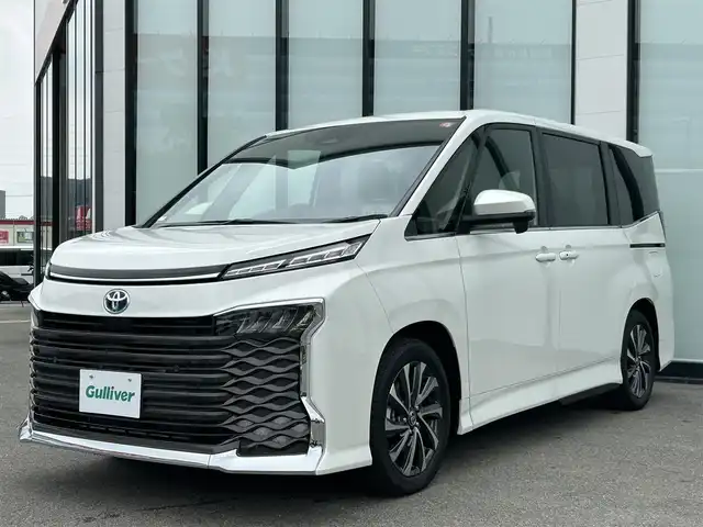 トヨタ ヴォクシー ハイブリッド S－Z 大阪府 2025(令7)年 0.1万km未満 ホワイトパールクリスタルシャイン 純正10.5インチナビ/  フルセグTV/Bluetooth/USB/100V電源/CD/DVDデッキ/バックモニター/ユニバーサルステップ/ブラインドスポットモニター/・安心降車アシスト/・状態時支援アドバンスドライブ/・レーンチェンジアシスト/快適利便パッケージ/・ハンズフリー両側パワースライドドア/・全席シートヒーター/・電動リアゲート/・ナノイーX/・オットマン/トヨタセーフティセンス/・レーンキープアシスト/・プリクラッシュセーフティ/・ハイビームアシスト/・レーダークルーズコントロール/横滑り防止装置/コーナーセンサー/純正17インチアルミホイール/純正フロアマット/プッシュスタート/スマートキー/ETC/LED/禁煙車