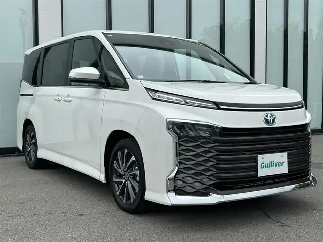 トヨタ ヴォクシー ハイブリッド S－Z 大阪府 2025(令7)年 0.1万km未満 ホワイトパールクリスタルシャイン 純正10.5インチナビ/  フルセグTV/Bluetooth/USB/100V電源/CD/DVDデッキ/バックモニター/ユニバーサルステップ/ブラインドスポットモニター/・安心降車アシスト/・状態時支援アドバンスドライブ/・レーンチェンジアシスト/快適利便パッケージ/・ハンズフリー両側パワースライドドア/・全席シートヒーター/・電動リアゲート/・ナノイーX/・オットマン/トヨタセーフティセンス/・レーンキープアシスト/・プリクラッシュセーフティ/・ハイビームアシスト/・レーダークルーズコントロール/横滑り防止装置/コーナーセンサー/純正17インチアルミホイール/純正フロアマット/プッシュスタート/スマートキー/ETC/LED/禁煙車