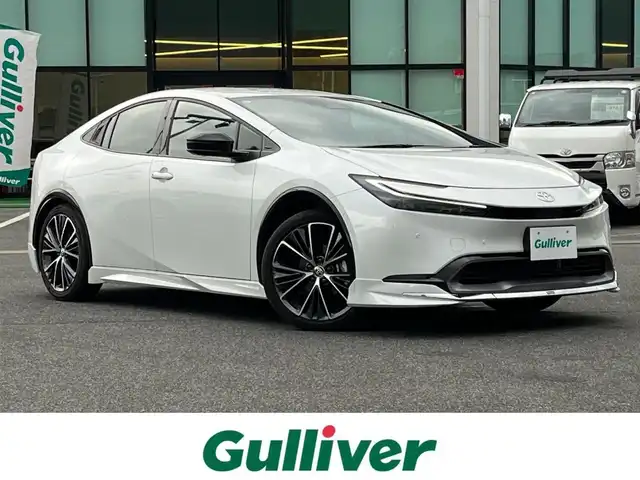 トヨタ プリウス Z 奈良県 2025(令7)年 1.3万km プラチナホワイトパールマイカ モデリスタエアロ/純正12インチディスプレイオーディオ/（TV/BT/AppleCarPlay/AndroidAuto）/レーダークルーズコントロール/アラウンドビューモニター/ブラインドスポットモニター/前後コーナーセンサー/プリクラッシュセーフティ/レーンキープアシスト/パーキングアシスト/パワーバックドア/レザーシート/運転席メモリ付きパワーシート/前席シートヒーター/エアーシート/ステアリングヒーター/ワイヤレス充電/デジタルインナーミラー/LEDヘッドライト/ETC2.0/純正19インチAW/保証書/取り扱い説明書