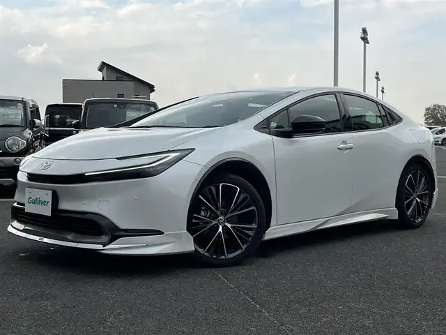 トヨタ プリウス Z 奈良県 2025(令7)年 1.3万km プラチナホワイトパールマイカ モデリスタエアロ/純正12インチディスプレイオーディオ/（TV/BT/AppleCarPlay/AndroidAuto）/レーダークルーズコントロール/アラウンドビューモニター/ブラインドスポットモニター/前後コーナーセンサー/プリクラッシュセーフティ/レーンキープアシスト/パーキングアシスト/パワーバックドア/レザーシート/運転席メモリ付きパワーシート/前席シートヒーター/エアーシート/ステアリングヒーター/ワイヤレス充電/デジタルインナーミラー/LEDヘッドライト/ETC2.0/純正19インチAW/保証書/取り扱い説明書
