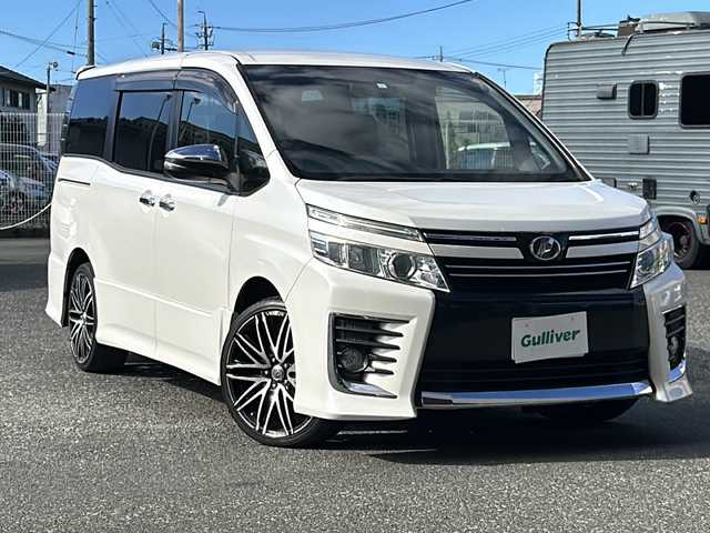 トヨタ ヴォクシー ZS 煌 愛知県 2015(平27)年 10.1万km ホワイトパールクリスタルシャイン 登録時走行距離100531km/社外8インチSDナビ/（フルセグTV/DVD/AM/FM/Bluetooth）/バックカメラ/アイドリングストップ/プッシュスタート/スマートキー/（スペアキー×１）/両側パワースライドドア/ビルドインETC/ドアバイザー/純正フロアマット/フォグランプ/オートライト/取説/保証書