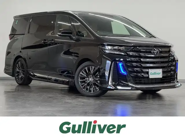 トヨタ ヴェルファイア ハイブリット Z プレミア 三重県 2024(令6)年 0.7万km ブラック ハイブリッド/FF/MTモード付フロアCVT/14型ナビ/（FM/AM/TV/Bluetooth/USB/iPod/Miracast/CarPlay/AndroidAuto）/13.2型 有機EL後席モニター V13T-R72F/パノラミックビューモニター（床下透過機能付）/モデリスタエアロ（F/S/R下）、シグネチャーイルミブレード/両側パワースライドドア/ドラレコ前後/ETC2.0/Toyota Safety Sense/●PCS、LTA、レーダークルコン、アダプティブハイビーム、RSA、PDA、緊急操舵支援＋前後クロストラフィックアラート*/●パーキングサポートブレーキ/・BSM/LCA/安心降車アシスト/・Advanced Drive/アドバンスト・パーク　など/装備/・【OP】デジタルインナーミラー/・【OP】ユニバーサルステップ（両側）/・左右独立ムーンルーフ/・プレミアムナッパ本革シート（茶）/・シートヒーター＆ベンチレーション（D/N/2nd）/・ステアリングヒーター/・パワーシート（Dメモリー付8way/N4way/2ndリクライニング＆オットマン）/・パワーバックドア/・HUD/・100Vコンセント（1500W）/・タッチトレーサーオペレーション/・3眼LEDヘッドランプ/・おくだけ充電/・19inAW/・保/・スマートキーx2/など