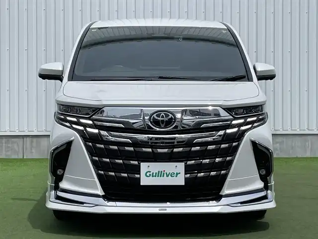 トヨタ アルファードハイブリット Z 香川県 2023(令5)年 1.6万km プラチナホワイトパールマイカ 登録時走行距離：15393km/メーカー純正ナビ/　BT フルセグTV/全方位カメラ/フリップダウンモニター/モデリスタエアロ/左右独立稼働型ムーンルーフ/ブラックレザーシート/シートベンチレーション/パワーシート/シートメモリ/オットマン/電動シェード/プリクラッシュセーフティシステム/レーンキープアシスト/レーダークルーズコントロール/クリアランスソナー/ブラインドスポットモニター/ヘッドアップディスプレイ/オートハイビーム/LEDヘッドライト/オートライト/フォグランプ/前後ドライブレコーダー/ビルトインETC2.0/MTモード付AT/横滑り防止装置/オートホールド機能付き電子パーキングブレーキ/置くだけ充電/AC100V充電/木目革巻きコンビステアリング/ステアリングスイッチ/ステアリングヒーター/プッシュスタート/スマートキー