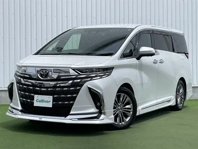トヨタ アルファードハイブリット Z 香川県 2023(令5)年 1.6万km プラチナホワイトパールマイカ 登録時走行距離：15393km/メーカー純正ナビ/　BT フルセグTV/全方位カメラ/フリップダウンモニター/モデリスタエアロ/左右独立稼働型ムーンルーフ/ブラックレザーシート/シートベンチレーション/パワーシート/シートメモリ/オットマン/電動シェード/プリクラッシュセーフティシステム/レーンキープアシスト/レーダークルーズコントロール/クリアランスソナー/ブラインドスポットモニター/ヘッドアップディスプレイ/オートハイビーム/LEDヘッドライト/オートライト/フォグランプ/前後ドライブレコーダー/ビルトインETC2.0/MTモード付AT/横滑り防止装置/オートホールド機能付き電子パーキングブレーキ/置くだけ充電/AC100V充電/木目革巻きコンビステアリング/ステアリングスイッチ/ステアリングヒーター/プッシュスタート/スマートキー