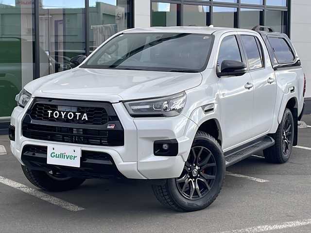 トヨタ ハイラックス Z GRスポーツ 道東・釧路十勝 2024(令6)年 1.1万km プラチナホワイトパールマイカ ・寒冷地仕様/・4WD/・純正ディスプレイオーディオ/(ナビ・FM・AM・BT・Miracast)/・全方位カメラ/・トヨタセーフティセンス/・プリクラッシュセーフティ/・レーンキープアシスト/・レーダークルーズコントロール/・ダウンヒルアシストコントロール/・横滑り防止/・GR専用シート/・純正マッドフラップ/・TRDフロアマット/・センターデフロック/・アイドリングストップ/・LEDヘッドライト/・オートライト/・社外キャノピー/・パドルシフト/・スマートキー/・プッシュスタート/・夏用タイヤ【2023年　4ミリ】　積込