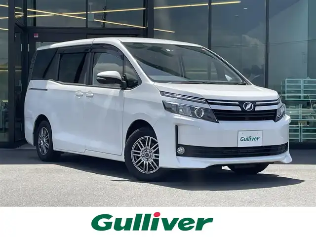 トヨタ ヴォクシー V 東京都 2014(平26)年 7.7万km ホワイトパールクリスタルシャイン 純正メモリナビ〔NSZT-W62G〕/BT/CD/DVD/フルセグTV/バックカメラ/片側パワースライドドア/クルーズコントロール/ビルトインETC/ドライブレコーダー/トヨタセーフティセンスC/　・プリクラッシュセーフティシステム/　・レーンディパーチャーアラート/　・オートマチックハイビーム/LEDオートライト/純正15インチアルミホイール/純正フロアマット/後席ロールサンシェード/MTモード付AT/フォグランプ/純正１６インチホイール付きサマータイヤ車載/プッシュスタート/スマートキー/保証書/整備記録簿/取扱説明書