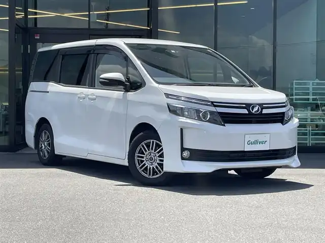 トヨタ ヴォクシー V 東京都 2014(平26)年 7.7万km ホワイトパールクリスタルシャイン 純正メモリナビ〔NSZT-W62G〕/BT/CD/DVD/フルセグTV/バックカメラ/片側パワースライドドア/クルーズコントロール/ビルトインETC/ドライブレコーダー/トヨタセーフティセンスC/　・プリクラッシュセーフティシステム/　・レーンディパーチャーアラート/　・オートマチックハイビーム/LEDオートライト/純正15インチアルミホイール/純正フロアマット/後席ロールサンシェード/MTモード付AT/フォグランプ/純正１６インチホイール付きサマータイヤ車載/プッシュスタート/スマートキー/保証書/整備記録簿/取扱説明書