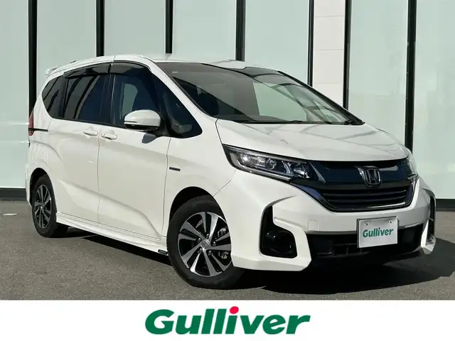 ホンダ フリード ハイブリット EX 大阪府 2019(令1)年 2.2万km ホワイトオーキッドパール 純正7インチナビ/　（CD/DVD/Bluetooth/USB/SD）/ホンダセンシング /モデューロエアロ/　（フロント、サイド、リア） /バックカメラ /ビルトインETC /Cパッケージ/　（プラズマクラスター搭載エアコン/ロールサンシェード/IR/UVカットガラス/コンフォートビューパッケージ）/Sパッケージ/　（本革巻きステアリング/コンビシート＆専用インテリア/15インチアルミホイール/シートバックアッパーポケット） /ハーフレザーシート/　（前席シートヒーター） /前後ドライブレコーダー /両側パワースライドドア/LEDヘッドライト/　（アクティブコーナリングライト）/純正フロアマット/　（ラゲッジマットなし）