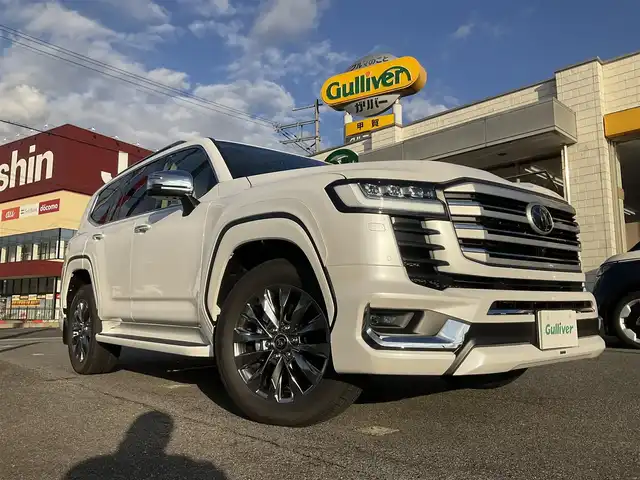 トヨタ ランドクルーザー ZX 滋賀県 2025(令7)年 0.1千km プレシャスホワイトパール ワンオーナー/車検10年9月まで/モデリスタエアロ（フロント、サイド、リア）/3列シート7人乗り/ブラックルーフレール/クールボックス/トノカバー/ムーンルーフ/タイヤ空気圧警報システム/トヨタセーフティセンス/ブラインドスポットモニター/レーダークルーズコントロール/12.3インチディスプレイオーディオプラス/フルセグテレビ、AppleCarPlay、AndroidAuto/JBLプレミアムサウンドシステム/後席11.6インチリアシートエンターテインメント/パノラミックビューモニター/ビルトインETC2.0/ベージュ革シート/前席パワーシート/前席、2列目ベンチレーション付き快適温熱シート/スペアキー有り/取扱説明書、保証書/