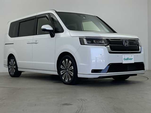 ホンダ ステップワゴン スパーダ eHEV プレミアムライン 鹿児島県 2023(令5)年 0.8万km プラチナホワイトパール 純正11インチナビ/（Bluetooth/フルセグTV/CD/DVD/USB接続）/純正フリップダウンモニター/マルチビューカメラ/パワーバックドア/パドルシフト/レーダークルーズコントロール/両側パワースライドドア/BSM/ハーフレザーシート/オットマン/オートライト/MUGENフロントグリル/ETC/前後ドライブレコーダー/純正フロアマット/純正17インチAW/スペアキー/AAC