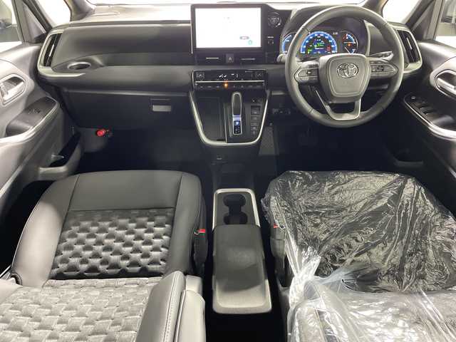 トヨタ ヴォクシー ハイブリッド 神奈川県 2025(令7)年 0.1千km プラチナホワイトパールマイカ ToyotaSafetySense/プリクラッシュセーフティ/緊急時操舵支援/フロントクロストラフィックアラート/レーントレーシングアシスト/レーンディパーチャーアラート/レーダークルーズコントロール/オートマチックハイビームシステム/ロードサインアシスト/ドライバー異常時対応システム/プロアクティブドライビングアシスト/発進遅れ告知機能/パーキングサポートブレーキ/(前後方静止物/後方接近車両)/(周囲静止物/後方歩行者)/アドバンストパーク/パノラミックビューモニター/ECO/PWR+EVモード/８インチディスプレイオーディオ/コネクティッドナビ/DTV/Bluetooth/スマホ連携/HDMI/快適便利パッケージ/ハンズフリーデュアルパワースライドドア/パワーバックドア/ステアリングヒーター/シートヒーター(前席・2列目)/オットマン/デジタルインナーミラー/AC100Vコンセント/ブレーキホールド/取説/ナビ説/保証書/スペアキー