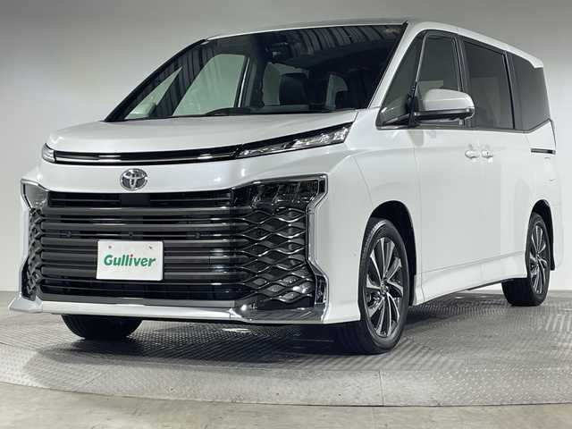 トヨタ ヴォクシー ハイブリッド 神奈川県 2025(令7)年 0.1千km プラチナホワイトパールマイカ ToyotaSafetySense/プリクラッシュセーフティ/緊急時操舵支援/フロントクロストラフィックアラート/レーントレーシングアシスト/レーンディパーチャーアラート/レーダークルーズコントロール/オートマチックハイビームシステム/ロードサインアシスト/ドライバー異常時対応システム/プロアクティブドライビングアシスト/発進遅れ告知機能/パーキングサポートブレーキ/(前後方静止物/後方接近車両)/(周囲静止物/後方歩行者)/アドバンストパーク/パノラミックビューモニター/ECO/PWR+EVモード/８インチディスプレイオーディオ/コネクティッドナビ/DTV/Bluetooth/スマホ連携/HDMI/快適便利パッケージ/ハンズフリーデュアルパワースライドドア/パワーバックドア/ステアリングヒーター/シートヒーター(前席・2列目)/オットマン/デジタルインナーミラー/AC100Vコンセント/ブレーキホールド/取説/ナビ説/保証書/スペアキー