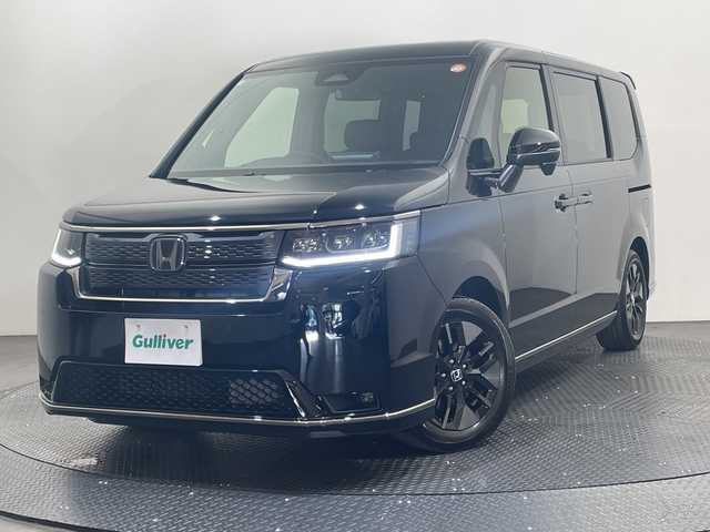 ホンダ ステップワゴン スパーダ eHEV 愛媛県 2025(令7)年 0.1千km クリスタルブラックパール 11.4インチナビHonda CONNECTナビ/Bluetooth/フルセグテレビ/バックカメラ/Honda CONNECT for Gathers/ナビ装着用スペシャルパッケージ/Honda SENSING/ブラインドスポットインフォメーション/パワーテールゲート(メモリー機能付)/2列目オットマン/ハーフレザーシート/運転席＆助手席シートヒーター/トリプルゾーンコントロール/フルオートエアコンディショナー/コンビシート/16インチアルミホイール(SPADA専用)/減速セレクター/全列USBチャージャー/LEDヘッドライト/両側パワースライドドア/スマートキー/追従型クルーズコントロール/前後コーナーセンサー