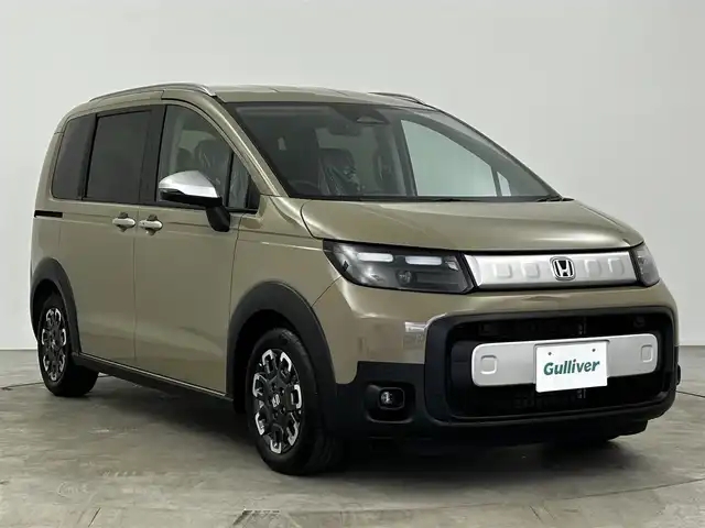 ホンダ フリード ハイブリット e:HEV クロスター 大分県 2025(令7)年 0.1千km ベージュ 純正9インチナビ（LXM-242ZFNI）/Bluetooth/フルセグ/Applecarplay/ホンダセンシング/・衝突被害軽減ブレーキ/・アダプティブクルーズコントロール/・車線維持支援システム/・誤発進抑制機能/・後方誤発進抑制機能/レーダークルコン/バックカメラ/コーナーセンサー/オートライト/オートホールドブレーキ/リアクーラー/シートヒーター/ステアリングスイッチ/革巻ステアリング/フォグランプ