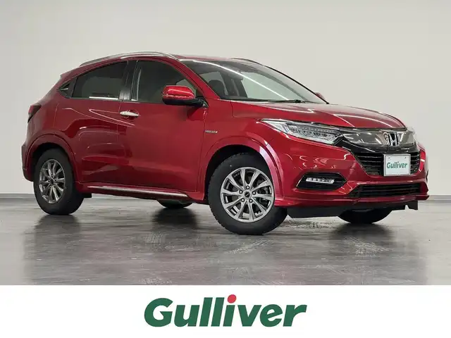 ホンダ ヴェゼル ハイブリッド Z ホンダセンシング 三重県 2019(令1)年 2.7万km プレミアムクリスタルレッドM ハイブリッド/FF/i-DCD（MTモード付フロア7DCT）/純正17inAWあり/純正 8インチナビ VXM-184VFi/（CD/DVD/RADIO/TV/SD/MusicRack/USB/iPod/Bluetooth/HDMI/AppleCarPlay）/バックカメラ/ビルトイン ETC/Honda SENSING/・衝突軽減ブレーキ［CMBS］/・車線維持支援システム［LKAS］/・アダプティブクルーズコントロール［ACC］/・路外逸脱抑制機能/・標識認識機能/・先行車発進お知らせ機能/・リアクティブフォースペダル［RFP］/装備/・ハーフレザーシート/・シートヒーター（D/N）/・左右独立オートエアコン/・雨滴検知オートワイパー/・パドルシフト/・電子パーキングブレーキ/・オートブレーキホールド/・自動防眩ルームミラー/・ステアリングスイッチ/・保/取/・スマートキーx2
