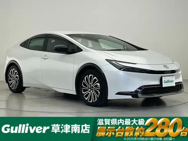 トヨタ プリウス Z 滋賀県 2023(令5)年 0.9万km プラチナホワイトパールマイカ 純正12.3型ナビ/（フルセグTV/BT/USB/Miracast/AppleCarplay）/トヨタセーフティセンス/・プリクラッシュセーフティ/・レーダークルーズコントロール（全車速追従）/・レーントレーシングアシスト（LTA）/・ロードサインアシスト/・アダプティブハイビームシステム/・オートマチックハイビーム/・パーキングサポートブレーキ（前後方・静止物）/・トヨタ チームメイト［アドバンストパーク］/・ブラインドスポットモニター（BSM）/・安心降車アシスト/・後方車両接近告知/・周辺車両接近時サポート/パノラミックビューモニター/ビルトインETC2.0/前後ドライブレコーダー/デジタルインナーミラー/クリアランスソナー/レザーシート/D席パワーシート/前席シートヒーター/シートベンチレーション/ステアリングヒーター/AC100V/LEDヘッドライト/純正フロアマット/モデリスタ17インチAW