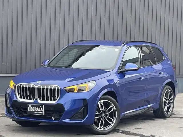 ＢＭＷ ＢＭＷ Ｘ１ xDrive 20i Mスポーツ 青森県 2023(令5)年 1.3万km 青 /ワンオーナー/4WD/車体色ポルティマオブルー(C31)/純正ディスプレイオーディオナビ　(BT/AM/FM/Spotify/AppleCarPlay/　/AndroidAuto)/ルームミラー一体型ETC/前席パワーシート/前席シートヒーター/ヘッドアップディスプレイ/革巻きステアリング/オーディオ/ステアスイッチ/パドルシフト/アダプティブクルーズコントロール/ターボチャージャー搭載車/Assisted Drive Mode/ABS/ダイナミックスタビリティコントロール/アダプティブヘッドライト/レーンチェンジアシスト/アラームシステム/オートライトコントロール/ハイビームアシスト/ヒルディセントコントロール/アダプティブブレーキアシスタント/強化走行ダイナミクス/パークアシスト/制限速度アシスト/スペアキー(スマートキー1本)/カードキー/純正フロアマット/純正19インチアルミホイール/車両/ETC取扱説明書/保証書