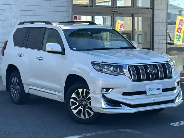 トヨタ ランドクルーザー プラド TX Lパッケージ 埼玉県 2023(令5)年 1万km ホワイトパールクリスタルシャイン 登録時9847km/4WD/サンルーフ/モデリスタエアロ/モデリスタウィングデッキ/純正9ナビ（AM/FM/フルセグTV/BT）/B/F/S/全方位カメラ/ビルトインETC2.0/アルパインデジタルインナーミラー/トヨタセーフティセンス/・踏み間違い防止アシスト/・ブレーキアシスト/・衝突軽減装置/・ヒルスタート（坂道発進）アシスト/・前方衝突防止支援システム/・ABS（アンチロックブレーキシステム）/・TCS（トラクションコントロールシステム）/・VDC（ビークルダイナミクスコントロール）/・ASCD（オートスピードコントロール装置）/・標識検知機能/・コーナーセンサー前後/運転席・助手席シートエアコン/本革シート/パワーシート（D＋N）/純正LEDヘッドライト/純正フロアマット/ルーフレール/電動格納ミラー/ステアリングスイッチ/オートライト/フロントフォグ/フルオートエアコン/プッシュスタート/スマートキー/スペアキー1本/保証書/車両/ナビ取扱説明書/セキュリティー有り/純正ルームミラー車載