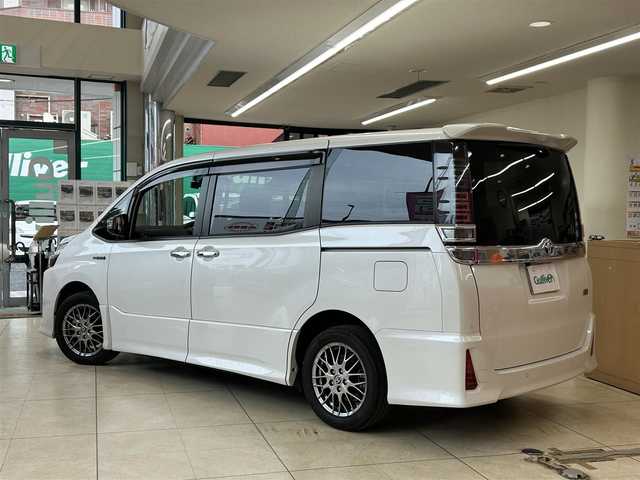 トヨタ ヴォクシー ハイブリッド ZS 煌Ⅱ 東京都 2019(令1)年 7.9万km ホワイトパールクリスタルシャイン ・純正10インチナビ/（NSZN-Z68T）/（CD/DVD/フルセグ/Bluetooth/HDMI）/・フリップダウン/・バックカメラ/・前後コーナーセンサー/・両側パワースライドドア/・前後ドライブレコーダー/・シートヒーター/・オートライト/・オートハイビーム/・LEDライト/・フロントフォグ/・衝突軽減システム/・LKA/・スマートキー/・プッシュスタート/・電動格納ミラー/・ETC2.0/・ステアリングスイッチ/・クルーズコントロール/・リアプライバシーガラス/・ISOFIX/・バイザー/・フロアマット/・純正16インチアルミホイール/・WSRS&ABS/・横滑り防止システム/・新車時保証書/・取扱説明書