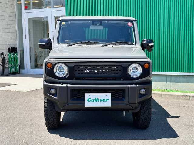 スズキ ジムニー XC 宮城県 2023(令5)年 0.4万km ミディアムグレー ワンオーナー/4WD/社外9インチSDナビ/【CD・DVD・SD・BT・HDMI・フルセグTV】/バックカメラ/純正16インチAW（マッドタイヤ・ホワイトレター）/クルーズコントロール/純正OPグリル/社外HKSマフラー/前席シートヒーター/アイドリングストップ/横滑り防止装置/レーンキープアラート/背面タイヤ/ステアリングスイッチ/電動格納ミラー/オートライト/LEDヘッドライト/LEDフォグ/スマートキーX２/ETC