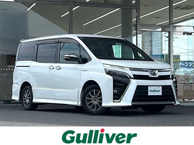トヨタ ヴォクシー ハイブリッド ZS 煌 福島県 2018(平30)年 9.4万km ホワイトパールクリスタルシャイン 登録時走行距離：93/676km/社外SDナビ/（フルセグTV/BT接続/AM/FM/CD/DVD）/社外フリップダウンモニター/両側パワースライドドア/バックカメラ/ETC/PUSHスタート/シートヒーター（D/N席）/クルーズコントロール/ステアリングスイッチ/ドライブレコーダー/電格ミラー/ウィンカーミラー/オートライト/オートハイビーム/LEDヘッドライト/フォグランプ/純正フロアマット/社外AW/スマートキー/スペアキー/ドアバイザー/サマータイヤ4本/レーンキープ/車両接近通報装置/衝突被害軽減ブレーキ/横滑り防止装置/三列シート/ウォークスルー/保証書/取扱説明書