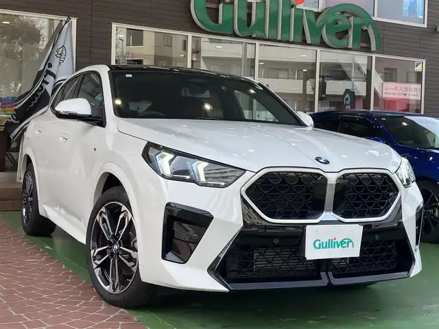 ＢＭＷ ＢＭＷ Ｘ２ xDrive 20i Mスポーツ 神奈川県 2024(令6)年 0.2万km アルピンホワイトⅢ ワンオーナー/新車保証書/取扱説明書/10.7インチHDDナビゲーション/10.25インチマルチディスプレイメーター/　（カープドディスプレイ）/全周囲カメラ/パノラマガラスサンルーフ/ブラックヴェガンザ/アルカンターラコンビシート/パワーシート/ミラー一体型ETC2.0/ハイラインパッケージ/・harman kardon HiFiスピーカーシステム/　（12スピーカー）/ドライビングアシストプロフェッショナル/・高速道路渋滞時ハンズオフアシスト/・アクティブクルーズコントロール/・レーンディパーチャーウォーニング/・レーンチェンジウォーニング/・衝突回避被害軽減ブレーキ/・前車接近警告機能/・クロストラフィックウォーニング/・スピードリミットインフォ/・エマージェンシーストップアシスト/・ステアリング/レーンコントロールアシスト/・レーンキーピングアシスト/・レーンチェンジアシスト/パーキングアシストプラス/・パーキングアシスト/・アクティブパークディスタンスコントロール/・サラウンドビューシステム/・リモート3Dビュー/・リバースアシスト/ストレージパッケージ/パワーバックドア