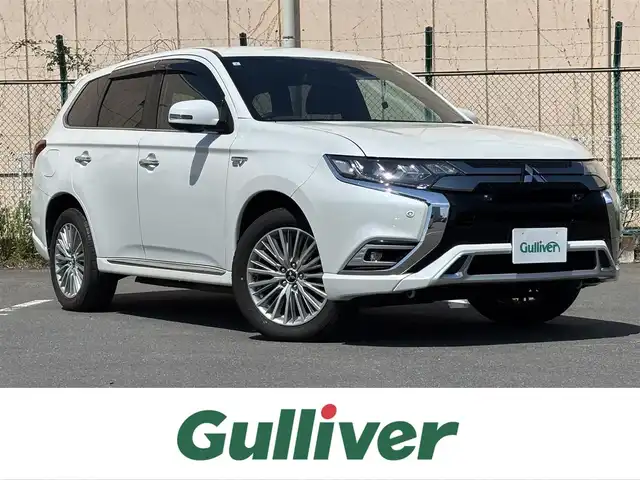 三菱 アウトランダー ＰＨＥＶ G プレミアムパッケージ 東京都 2019(平31)年 11.5万km シルキーホワイト S-AWC(アクティブヨー/アクティブスタビリティコントロール統合制御）/充電機能（普通/急速）/充電口ロック（ドアロック連動）/eアシスト（予防安全技術）/パワーバックドア　/ボディ同色ミラー（電動格納機能/ヒーター/ウィンカー付）/モーフィンブラックインパネ加飾/ブラック天井/ハイコントラストメーター（自発光式アナログメーター/マルチインフォメーションディスプレイ）/シルバー加飾付革巻きステアリングホイール/ステアリングヒーター/ステアリングスイッチ（オーディオ/アダプティブクルーズコントロール）/パドルシフト/SRSエアバック（運転席/助手席/サイド/ニー/カーテン）/左右独立温度調節機能オートエアコン/リアヒーターダクト/パワーシート（運転席/助手席）/シートヒーター（運転席/助手席）/キーレスオペレーションシステム/パワースイッチ/MMCS/６スピーカー/マルチアラウンドモニター/AC電源100V/1500W/リモートコントロール（タイマー充電/空調/車両情報/車両操作）/ディスプレイオーディオ