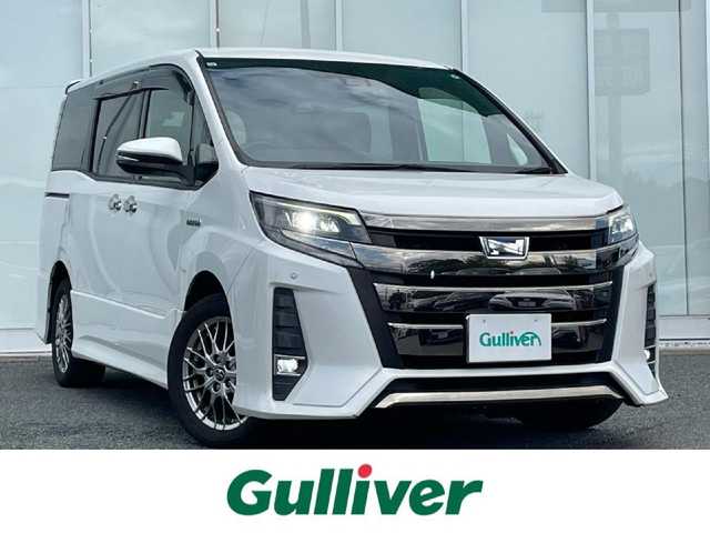 トヨタ ノア ハイブリッド Si ダブルバイビー 福岡県 2018(平30)年 8.9万km ホワイトパールクリスタルシャイン 純正9インチナビ/（AM/FM/SD/SDREC/BT/CD/DVD/フルセグ）/純正12.1インチフリップダウンモニター/クルーズコントロール/前後コーナーセンサー/レーンキープアシスト/プリクラッシュセーフティ/オートハイビーム/ETC/バックカメラ/前後ドライブレコーダー/両側パワースライドドア/純正16インチアルミホイール/純正フロアマット/純正ドアバイザー/ハーフレザーシート/D+N席シートヒーター/オートライト/LEDヘッドライト/フォグランプ/WAC/後席サンシェード/プッシュスタート/スマートキー/スペアキー/スタッドレスタイヤ4本付き/取扱説明書・保証書