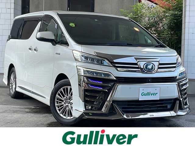トヨタ ヴェルファイア ハイブリット ZR Gエディション 京都府 2018(平30)年 9万km ホワイトパールクリスタルシャイン ＪＢＬメーカーナビ/AM/FM/AUX/HDMI/USB/Bluetooth/フルセグＴＶ/（キャンセラー付き）/全方位モニター/サンルーフ/純正フリップダウンモニター/モデリスタフルエアロ/　（マフラーカッター）/三眼ＬＥＤヘッドライト/レーダークルーズコントロール/両側パワースライドドア/電動リアゲート/トヨタセーフティーセンス/LEDシグネチャーイルミブレード/デジタルミラー/ブラインドスポットモニター/メモリー付きパワーシート/デュアルエアコン/レザーシート/前席ベンチレーション/前席シートヒーター/ステアリングヒーター/ビルトイン2.0ETC/前方ドライブレコーダー/盗難防止装置/（社外セキュリティ）/100V電源/プッシュスタート/スマートキー/3列シート/オットマン/ウォークスルー/レーンキープアシスト/横滑り防止装置/前後コーナーセンサー/オートマチックハイビーム/AFS/（アダクティブフロントライティングシステム）/ダブルエアバッグ+サイドエアバッグ/フォグライト