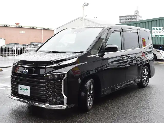 トヨタ ヴォクシー ハイブリッド S－Z 福岡県 2025(令7)年 0.2万km アティチュードブラックマイカ ワンオーナー/トヨタセーフティセンス/快適利便パッケージ(High)/純正OP10.5インチディスプレイオーディオ/フルセグ/CD/DVD/BT/HDMI/パノラミックビューモニター/純正OP13．2型後席ディスプレイ/純正OP3眼LEDヘッドライト/純正OPブラインドスポットモニター/純正OPアドバンストパーク/純正OPパーキングブレーキサポート/純正OPカラーヘッドアップディスプレイ/純正OPデジタルインナーミラー/純正ラグジュアリーフロアマット/純正GRスポーツサイドバイザー/TZ前後ドライブレコーダー/両側パワースライドドア/リア5面スモークフィルム/ビルトインETC2.0/新車時保証書/取扱説明書