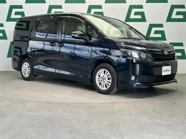 トヨタ ヴォクシー V 鹿児島県 2014(平26)年 7.9万km ブラッキッシュアゲハガラスフレーク 純正9インチSDナビ（NSZT-Y64T）/純正フリップダウンモニター（TVキャンセラー付き）/バックカメラ/フルセグTV/両側パワースライドドア/ビルトインETC/トヨタセーフティセンスC/クルーズコントロール/レーンキープアシスト/革巻きステアリング/オートライト/LEDヘッドライト/フロントフォグ/アイドリングストップ/純正フロアマット/純正アルミホイール/禁煙車